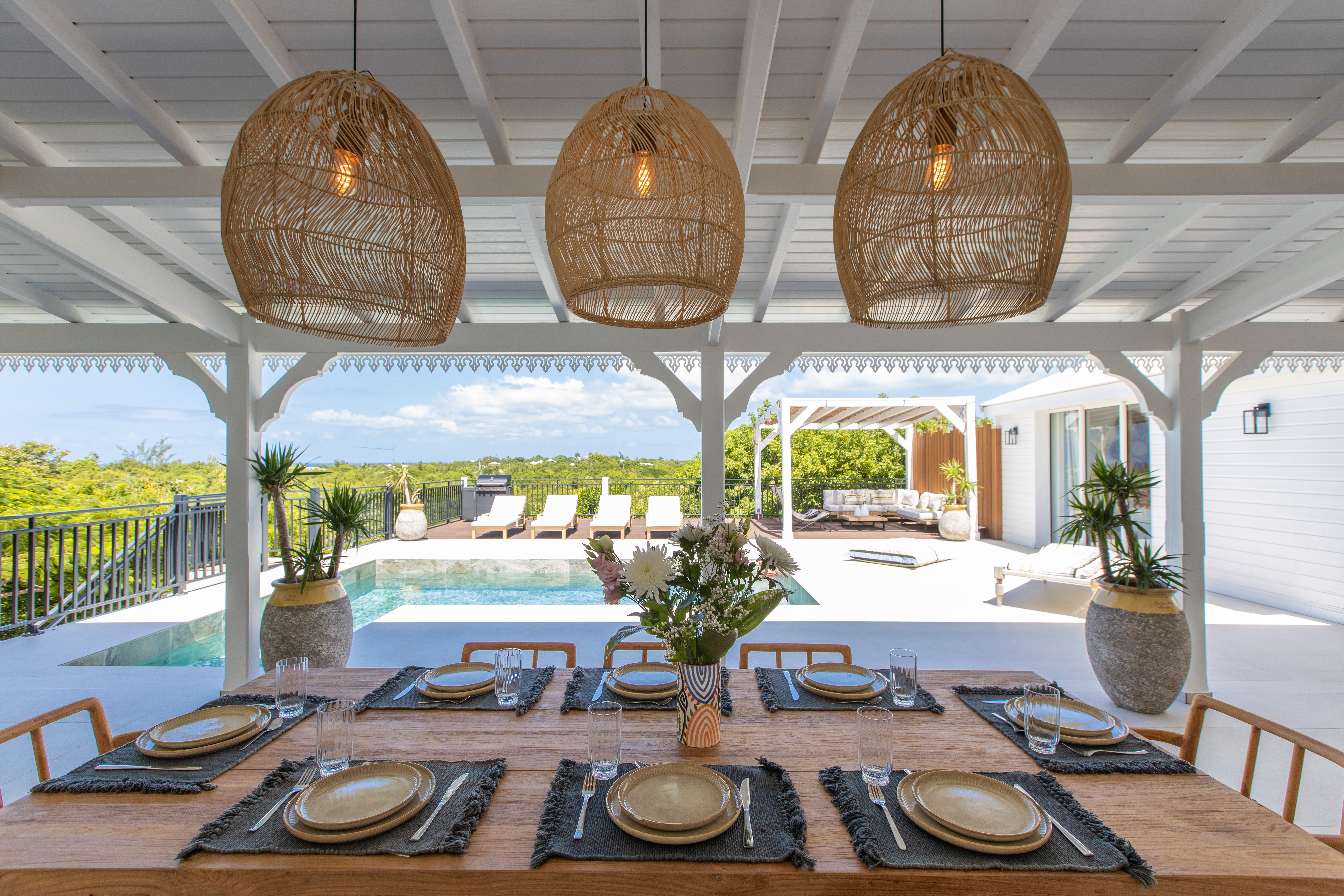 Dining table set beneath the veranda, overlooking the pool
