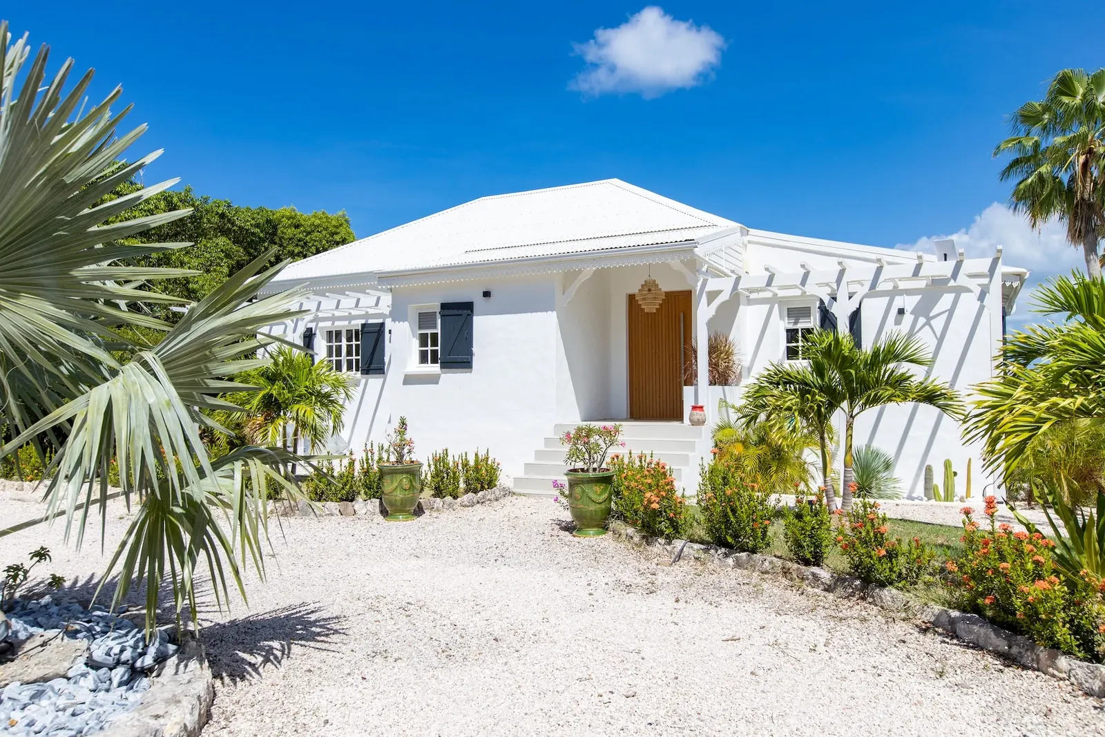 Façade blanche et entrée de Villa Les Oliviers dans le jardin tropical, Les Terres Basses, Saint-Martin